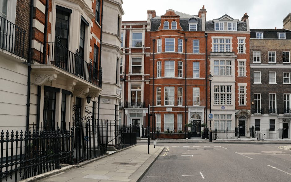 A street scene in Belgravia featuring a large white multi-story building with multiple evenly spaced sash windows and decorative greenery on the ground floor. Several black lampposts line the pavement